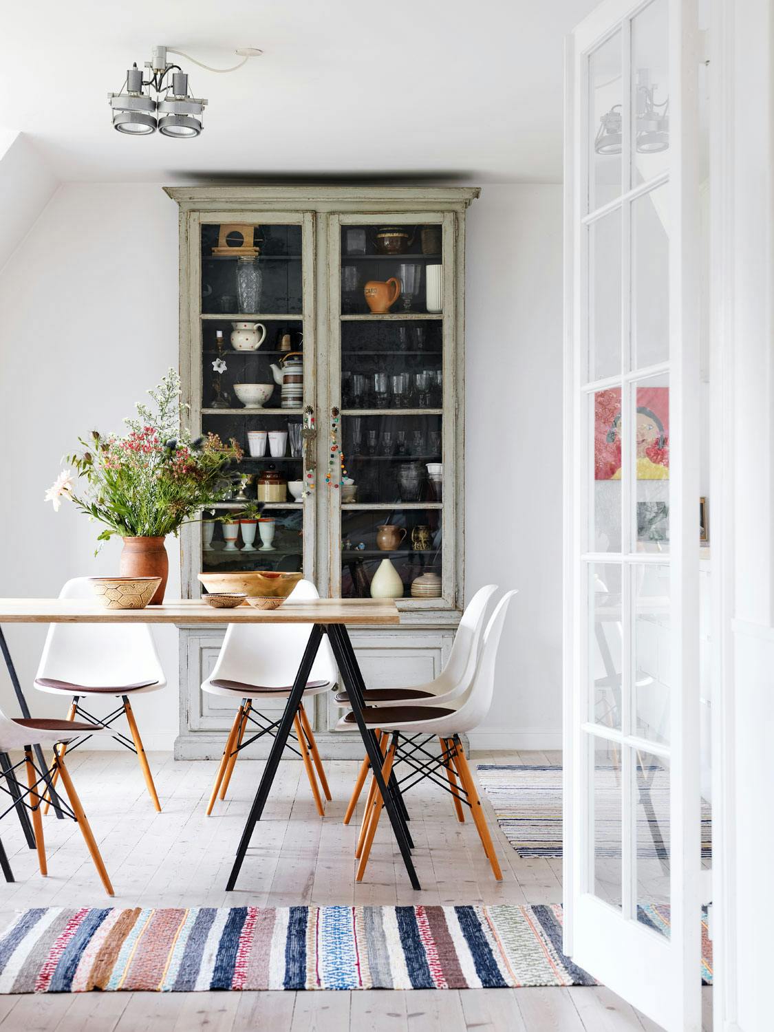 Vintage og designklassikere i balanse Klassisk spisestue med vintage grønt vitrineskap og Eames-stoler